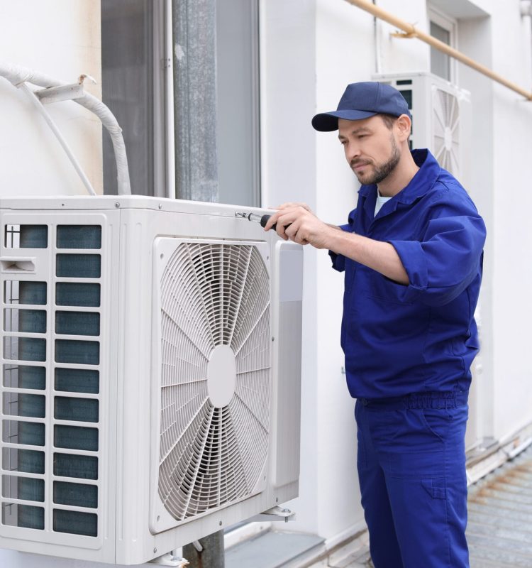 Male technician repairing air conditioner outdoors
