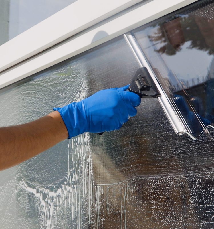 Male professional cleaning service worker in overalls cleans the windows and shop windows of a store with special equipment.